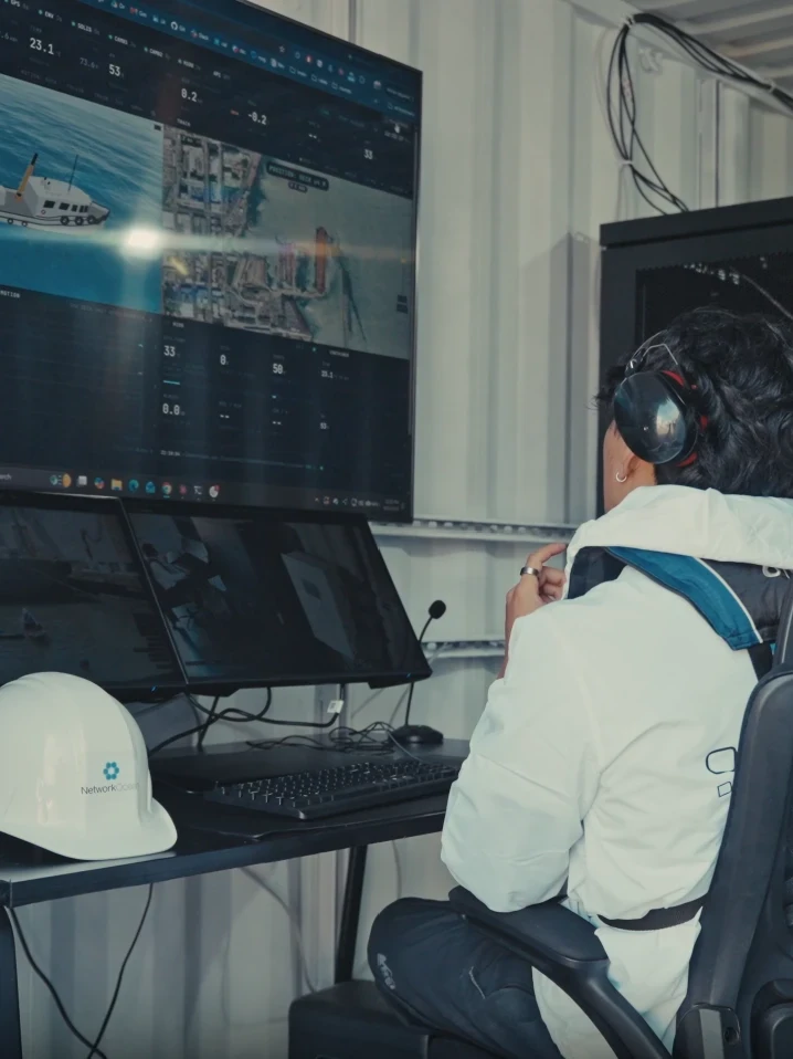 inside the container, the ops station, its wall screen showing the tow vessel and the power readings