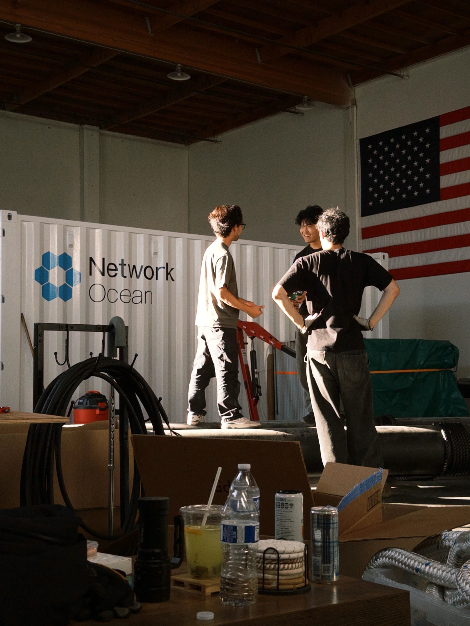 three of the team talking beside the container in the workshop